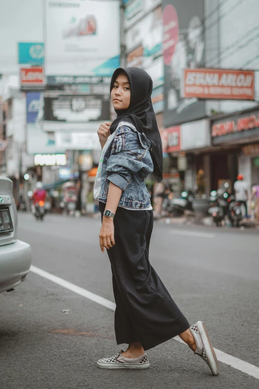 a woman crossing the street in front of a car, by Basuki Abdullah, pexels contest winner, hurufiyya, wearing a jeans jackets, wearing black robe, casual pose, square