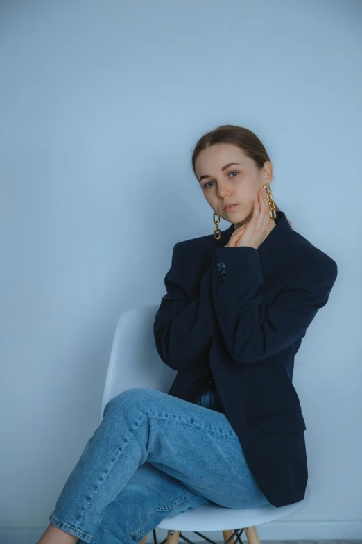 a woman sitting on top of a white chair, an album cover, inspired by Ilka Gedő, trending on pexels, antipodeans, wearing blue jacket, thoughtful pose, saoirse ronan, casual pose