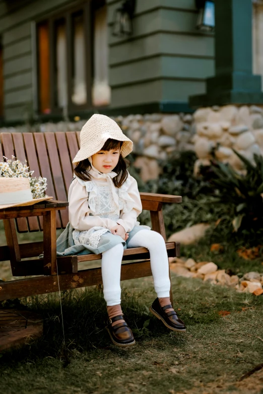 a little girl sitting on top of a wooden bench, sitting on a chair, wearing farm clothes, vanilla, cottagecore