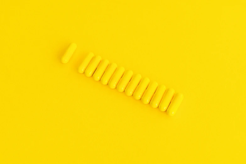 a row of yellow pills on a yellow background, by Pamphilus, trending on pexels, op art, tiny sticks, minimalist abstract art, vibrant threads, instagram post