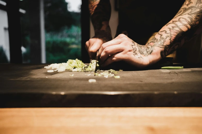 a close up of a person cutting food on a table, pexels contest winner, tattooed, sydney hanson, as chefs inside cthulhu, gardening