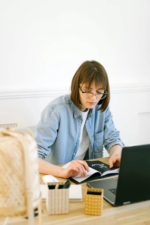 a woman sitting at a table working on a laptop, school curriculum expert, with two front pockets, curated collections, non-binary