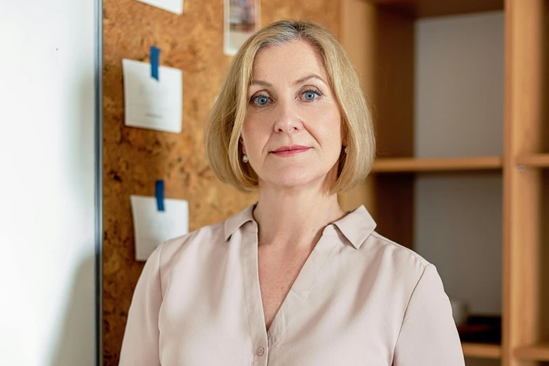 a woman standing in front of a bulletin board, by Emma Andijewska, portrait image