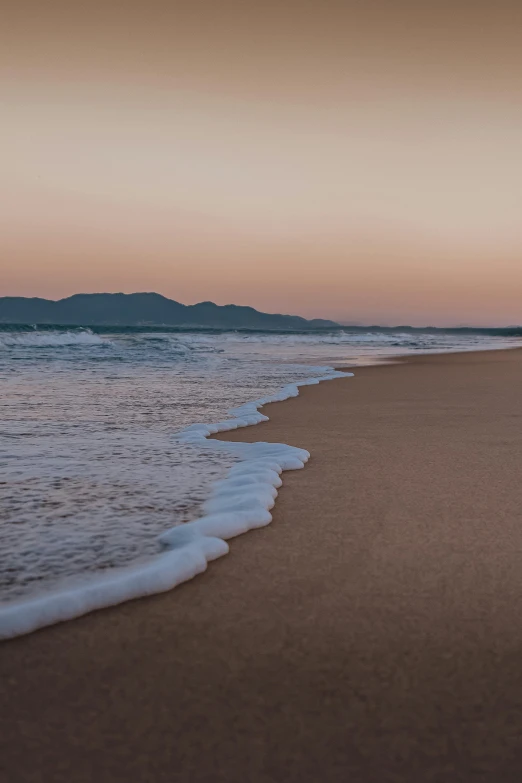 a person riding a surfboard on top of a sandy beach, eden at dawn, today\'s featured photograph 4k, mountains and ocean, lê long