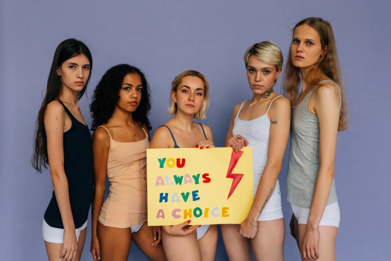 a group of women standing next to each other holding a sign, trending on pexels, homoerotic, bella poarch, wearing a tanktop, acceptance