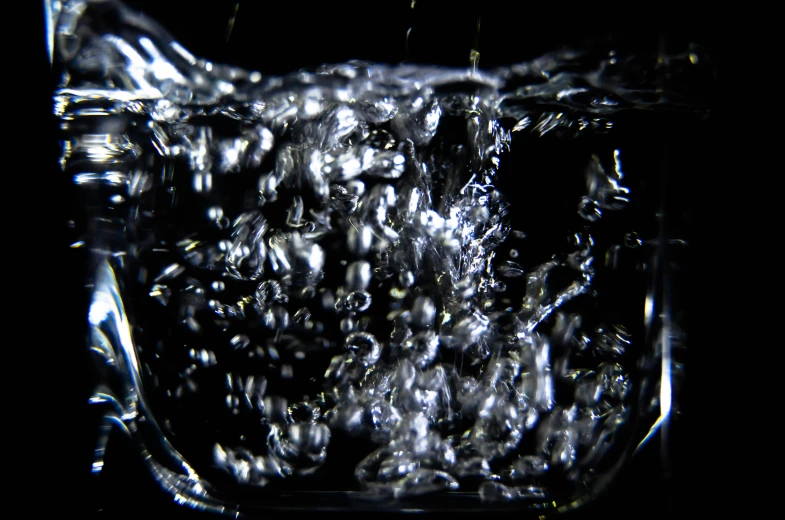 a glass filled with water sitting on top of a table, by Leo Michelson, pexels, video art, underwater caustics, black-water-background, bubbles rising, octane render - n 9