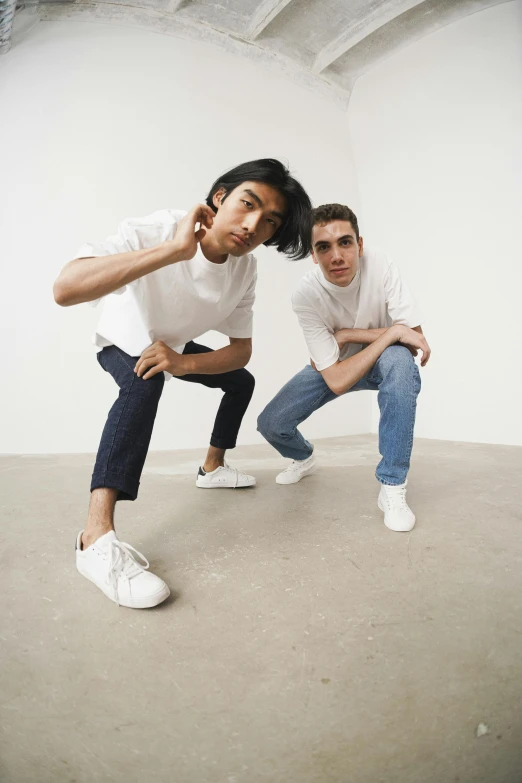 a couple of people that are posing for a picture, wearing white sneakers, in an action pose, two men, jeans and t shirt