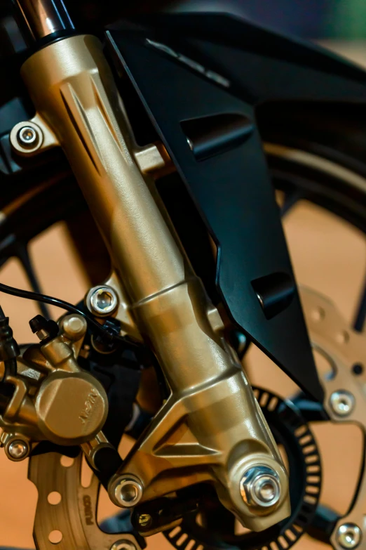 a close up of the front wheel of a motorcycle, gold and black metal, detailed product shot, high detail photograph, cubic