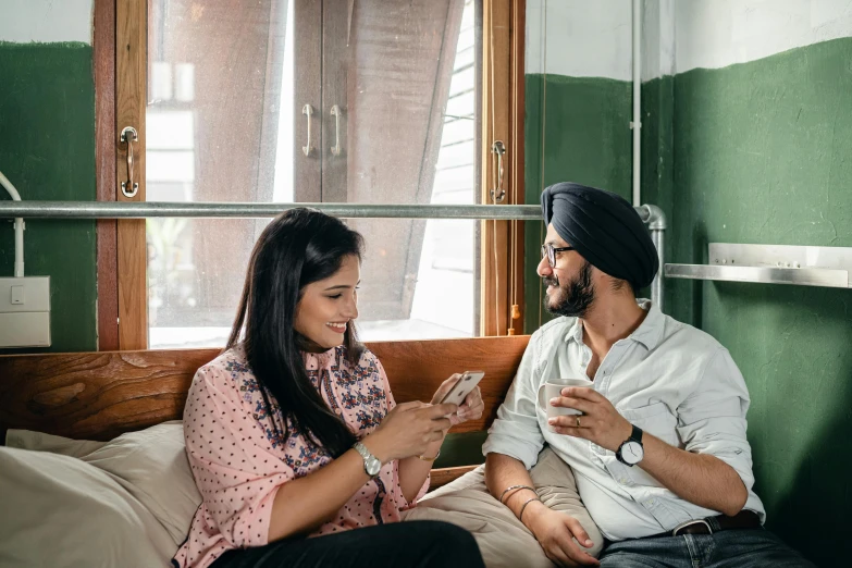 a man and a woman sitting on a bed, inspired by Manjit Bawa, trending on pexels, holds a smart phone in one hand, in a pub, avatar image, australian