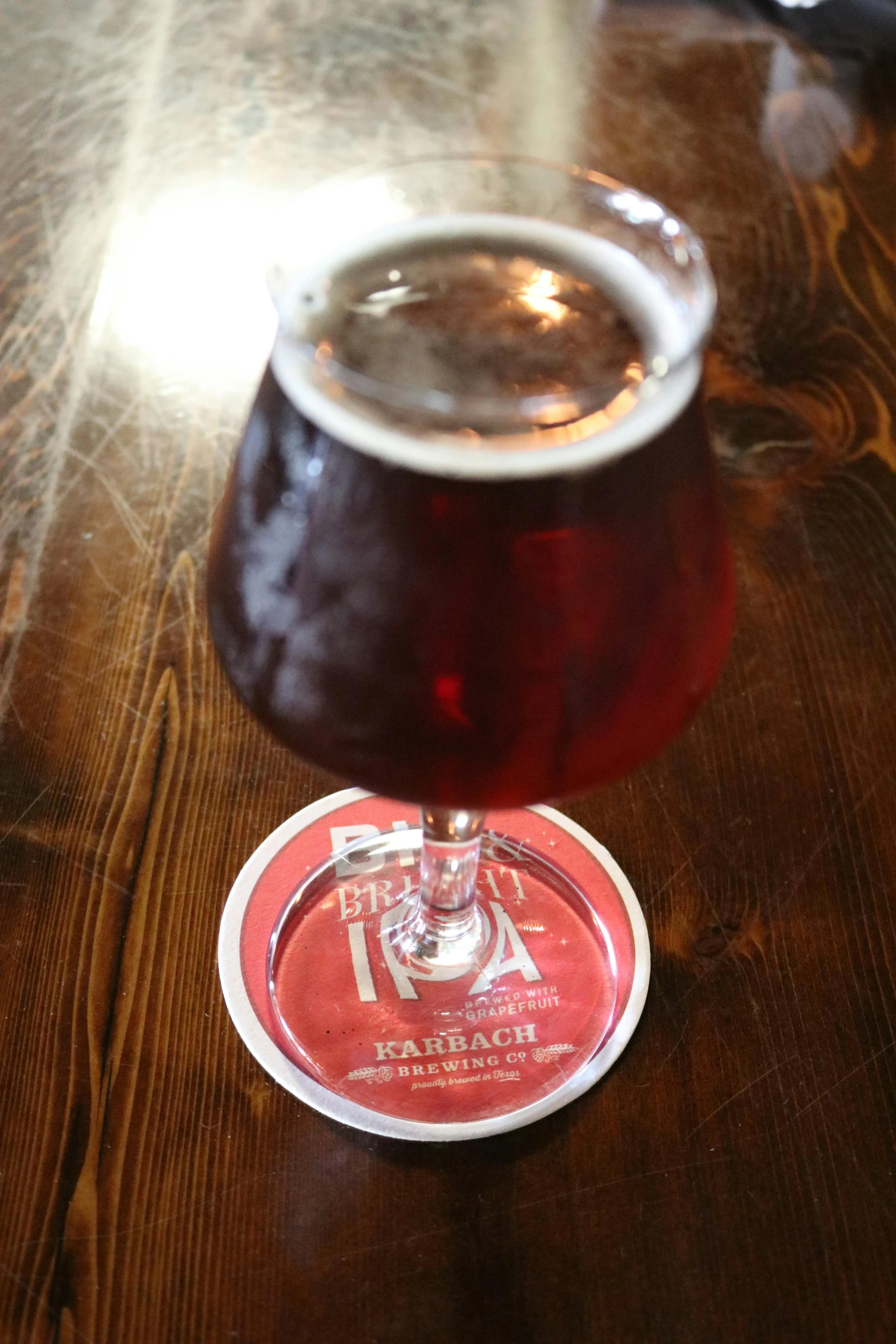 a glass of beer sitting on top of a wooden table, crimson themed, tribarrel, matchach, thumbnail