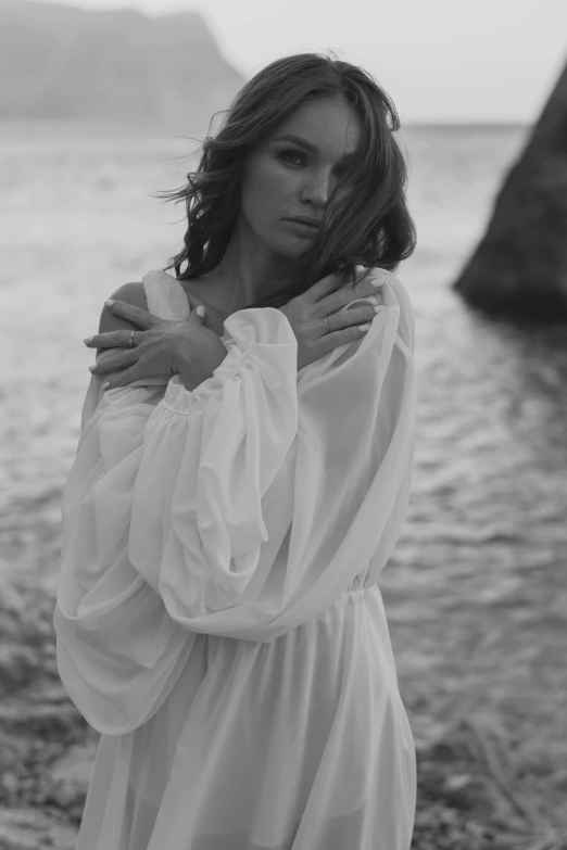 a woman standing in front of a body of water, a black and white photo, by Alexis Grimou, renaissance, soft silk dress, close-up shoot, white tunic, medium format. soft light