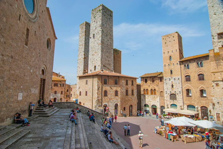 a group of people walking down a street next to tall buildings, inspired by Francesco del Cossa, pexels contest winner, renaissance, bargello, village square, two organic looking towers, sitting