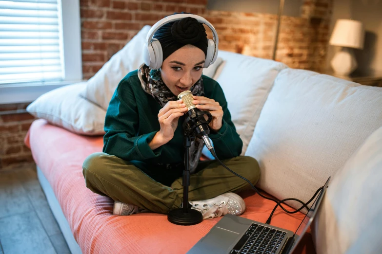 a woman sitting on a couch with a laptop and headphones, inspired by Maryam Hashemi, hurufiyya, eating garlic bread, sitting in front of a microphone, bong, modest