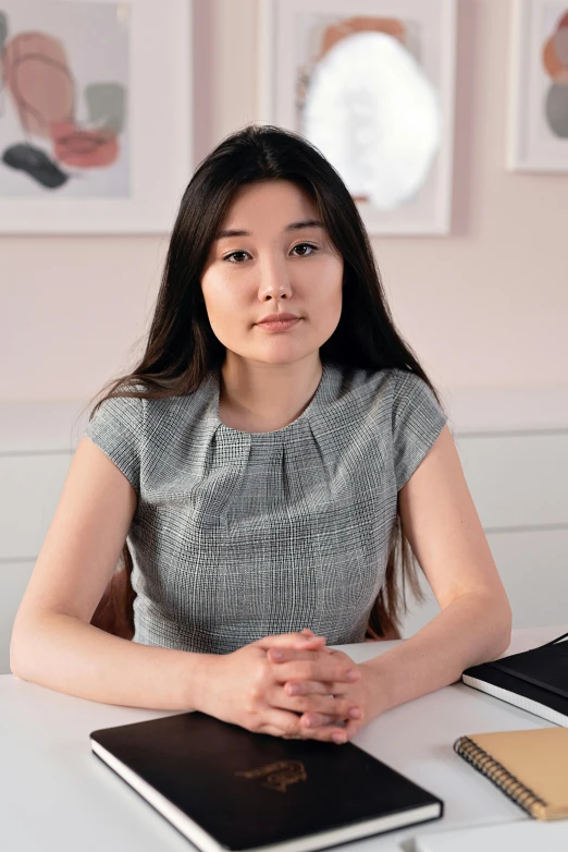 a woman sitting at a desk in front of a laptop computer, a picture, inspired by Feng Zhu, wearing a designer top, product introduction photo, arms crossed on chest, grey