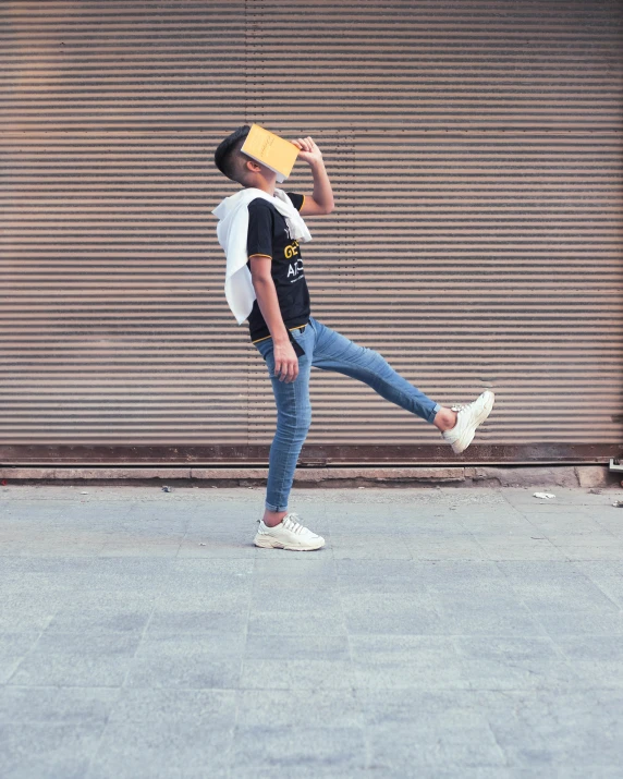 a man standing on a skateboard in front of a garage door, by Cosmo Alexander, pexels contest winner, holding a book, yellow cap, jumping for joy, non-binary