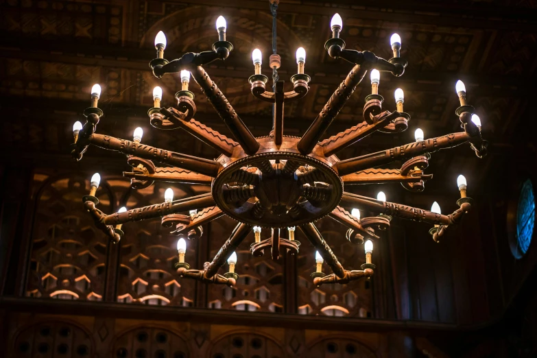 a chandelier hanging from the ceiling of a church, inspired by Charles Gleyre, pexels contest winner, arts and crafts movement, carved in wood, in the gryffindor common room, artificial lighting, brown