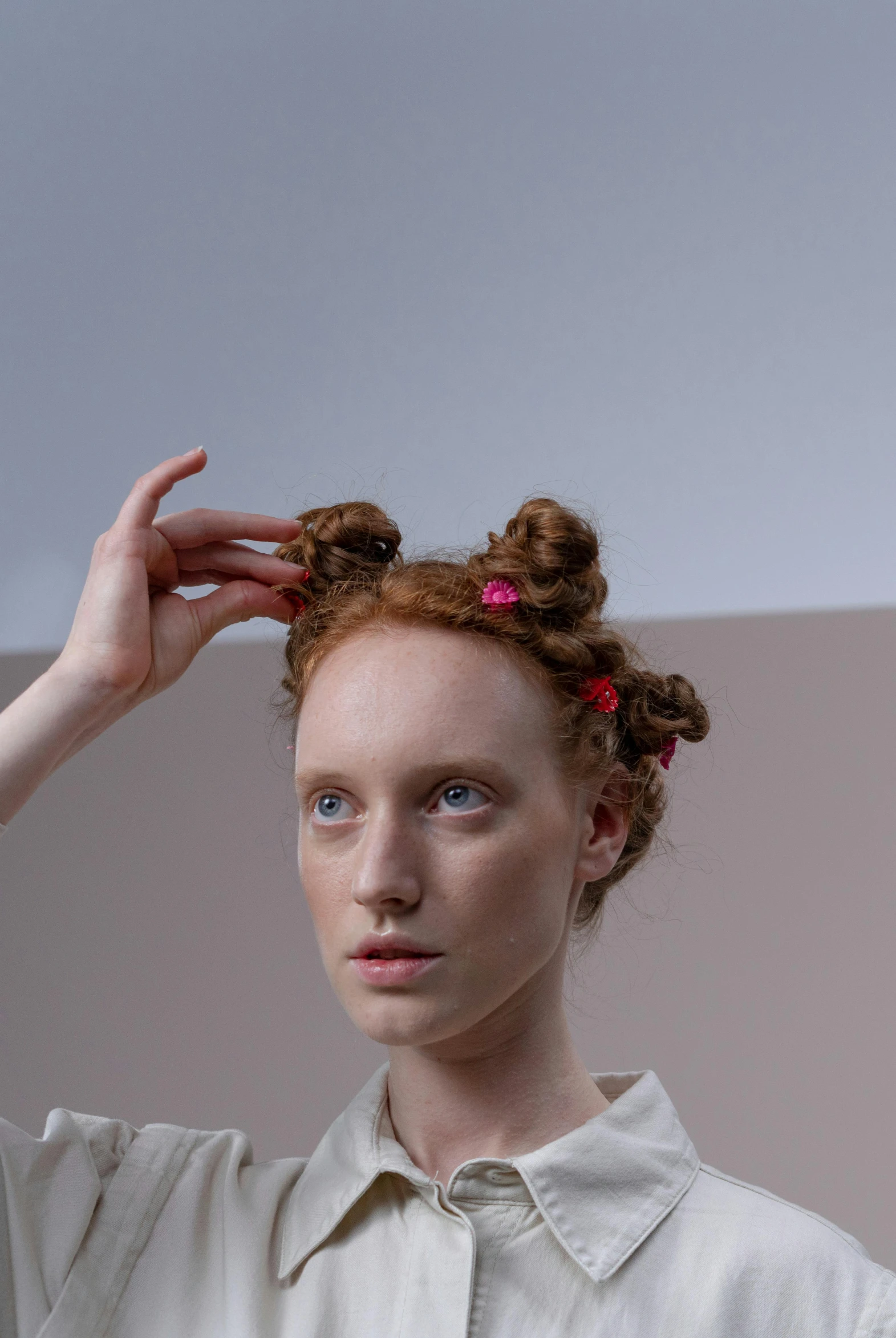 a woman with red hair standing in front of a mirror, inspired by Anna Füssli, trending on pexels, renaissance, hair styled in a bun, on grey background, hair loops, comme des garcon campaign