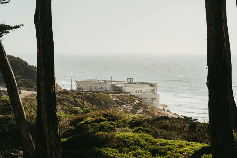 a house sitting on top of a hill next to the ocean, by Lee Loughridge, unsplash contest winner, joel meyerowitz, exterior view, military outpost, private school