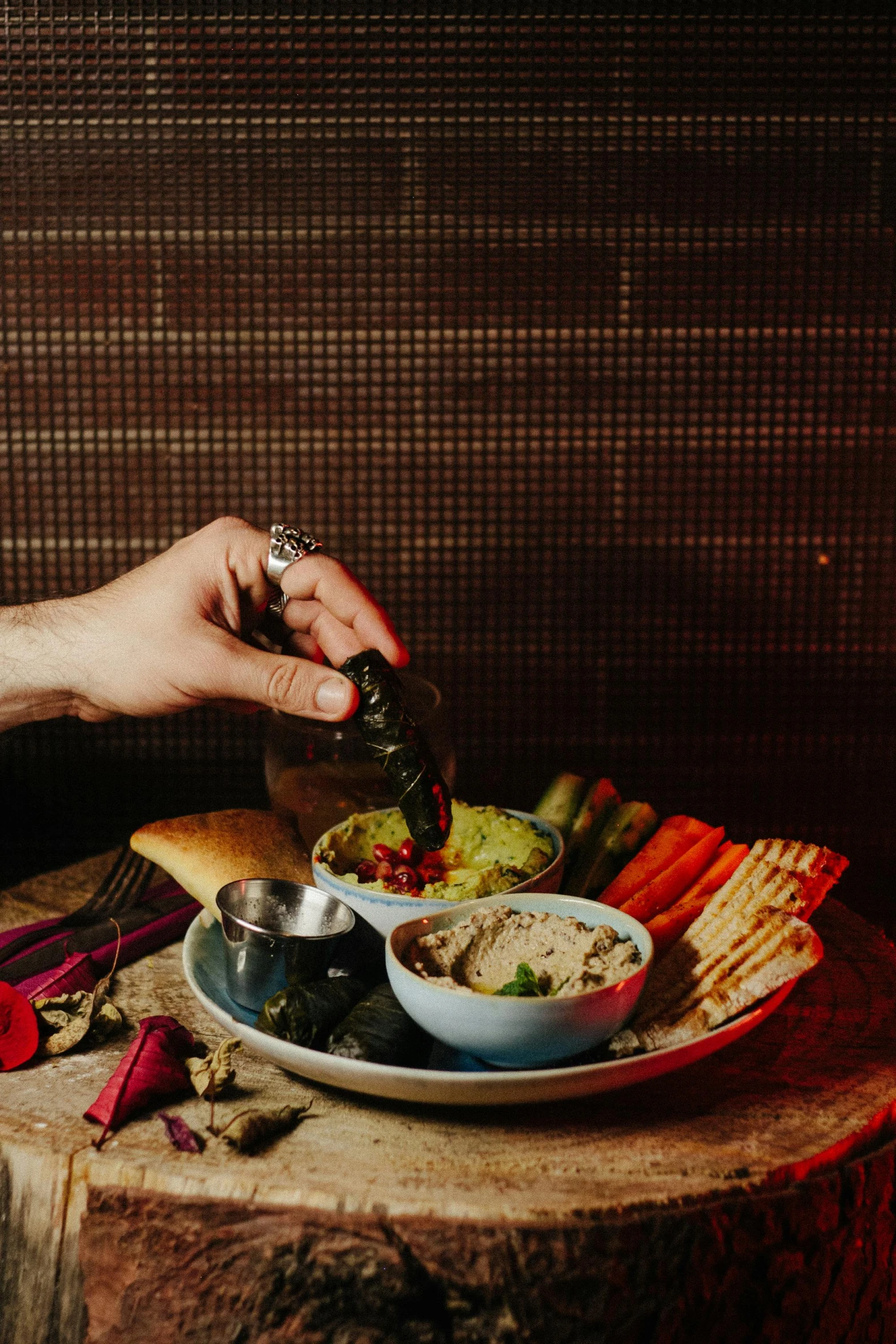 a person sitting at a table with a plate of food, humus, moody vibe, background bar, hands retouched