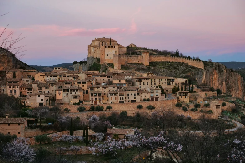 a small town sitting on top of a hill, inspired by Serafino De Tivoli, pexels contest winner, renaissance, pink, albert ramon puig, beige, at twilight