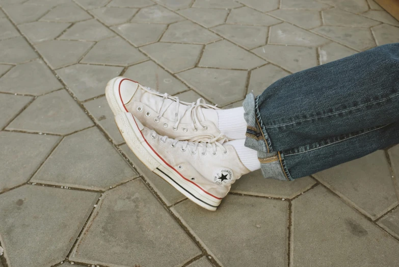 a person sitting on the ground with their feet on a skateboard, inspired by Elsa Bleda, trending on pexels, photorealism, wearing red converse shoes, cream, ( ( ( wearing jeans ) ) ), beige