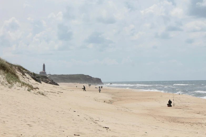 a group of people sitting on top of a sandy beach, a road leading to the lighthouse, walking on the sand, malika favre, listing image