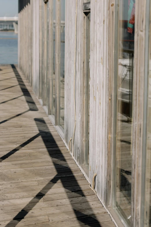 a red fire hydrant sitting on top of a wooden pier, inspired by Peter Zumthor, unsplash, modernism, nesting glass doors, long shadows, transparent corrugated glass, in a row