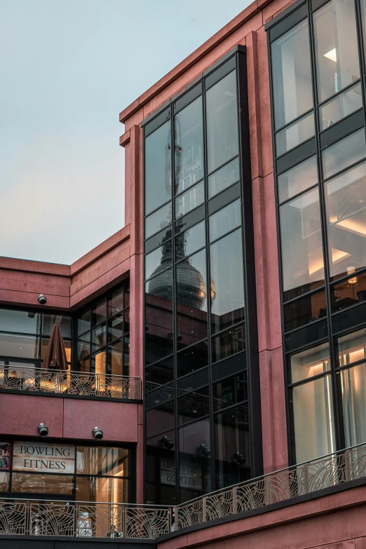 a tall building with a clock on top of it, in the evening, large glass windows, payne's grey and venetian red, view from behind