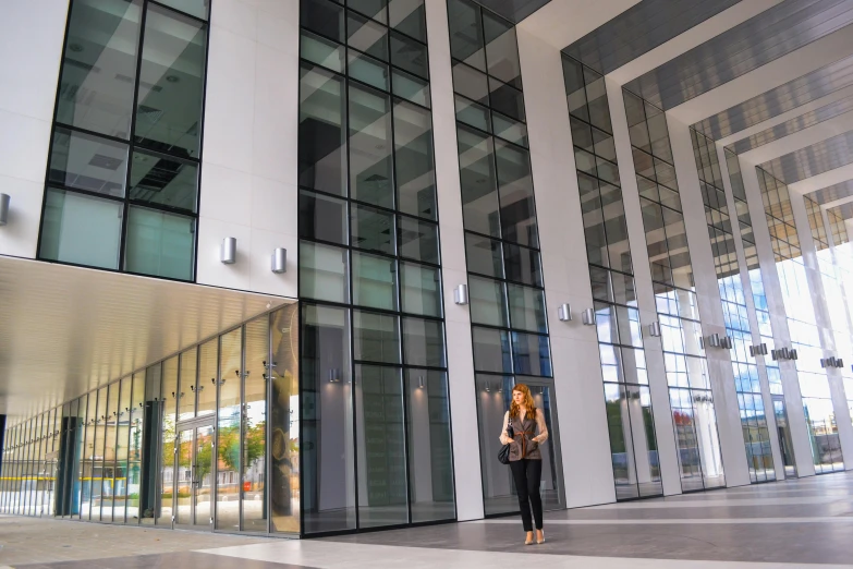 a woman standing in front of a large building, modern technology building, coventry city centre, office ceiling panels, thumbnail