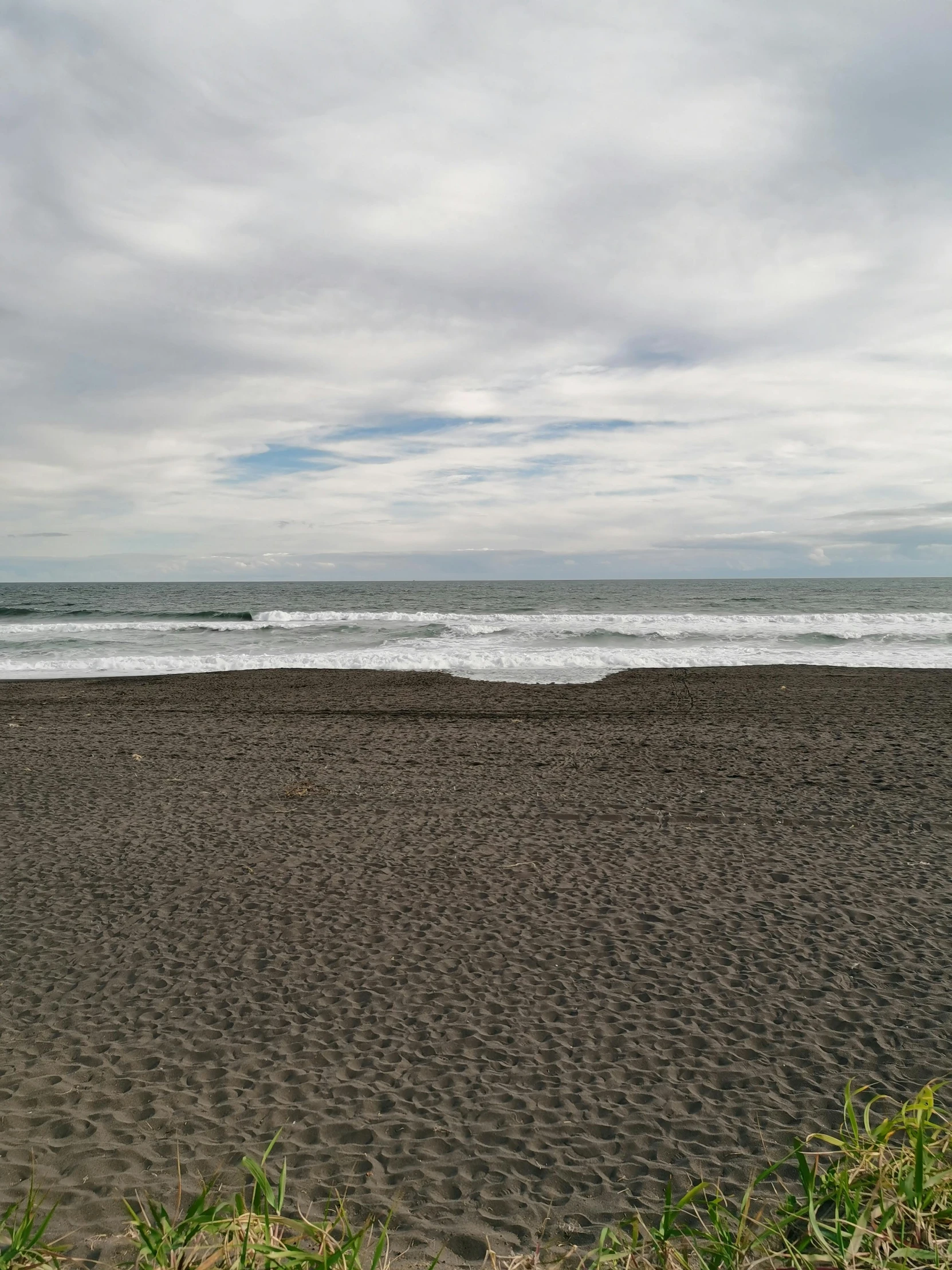 a man riding a surfboard on top of a sandy beach, black sand, highly detailed # no filter, overcast!!!, photo 8 k