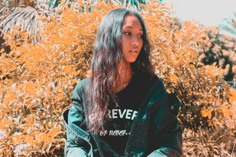 a woman sitting on a bench in front of a bush, an album cover, by Robbie Trevino, trending on pexels, sumatraism, in a hoodie, avatar image, black teenage girl, profile photo