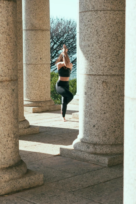 a woman in a black top doing a yoga pose, a statue, pexels contest winner, arabesque, colonnade, leggings, in spain, bay area