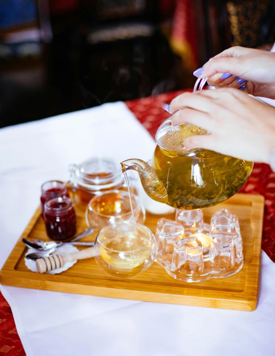 a person pouring tea into a glass pitcher, by Julia Pishtar, pexels, carrying a tray, honey, square, 15081959 21121991 01012000 4k