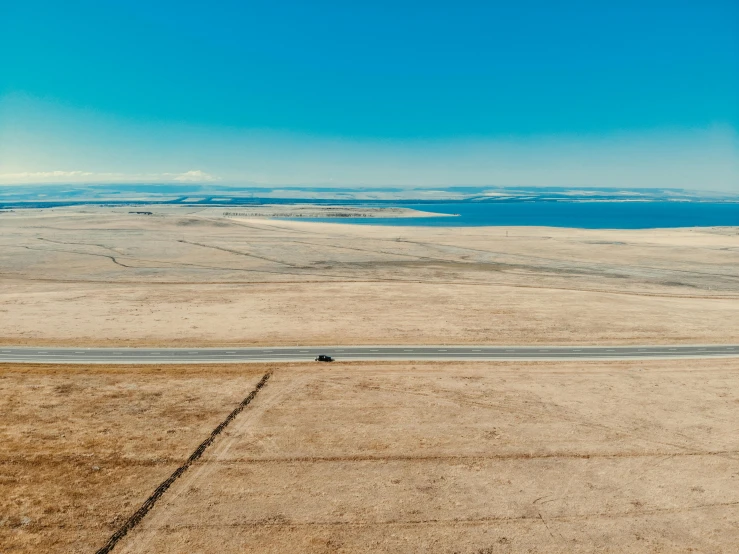 an aerial view of a road in the middle of nowhere, by Jeffrey Smith, pexels contest winner, land art, lake in the distance, scenic prairie in background, car shot, panorama distant view