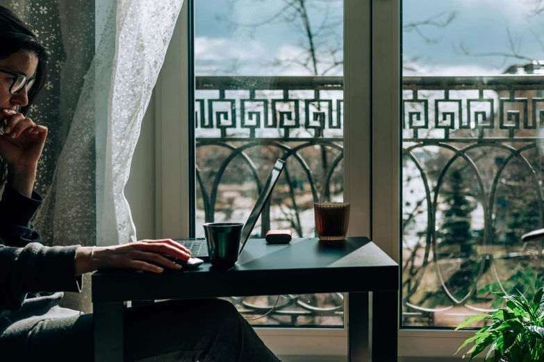 a person sitting at a table with a laptop, inspired by Elsa Bleda, window view, paris hotel style, coffee smell, lake view