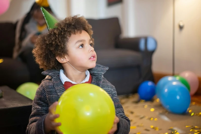 a young boy in a party hat holding a balloon, pexels contest winner, mixed race, looking across the shoulder, children's, thumbnail