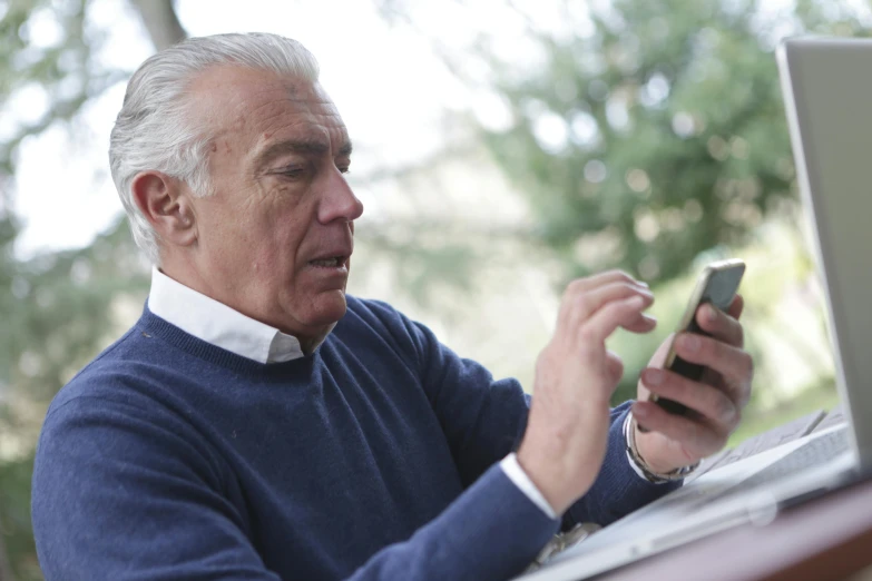 a man sitting at a table with a laptop and a cell phone