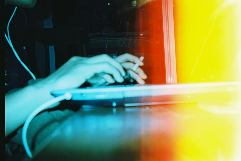 a close up of a person typing on a laptop, inspired by Elsa Bleda, computer art, red and yellow light, lomography photo, holographic, thumbnail