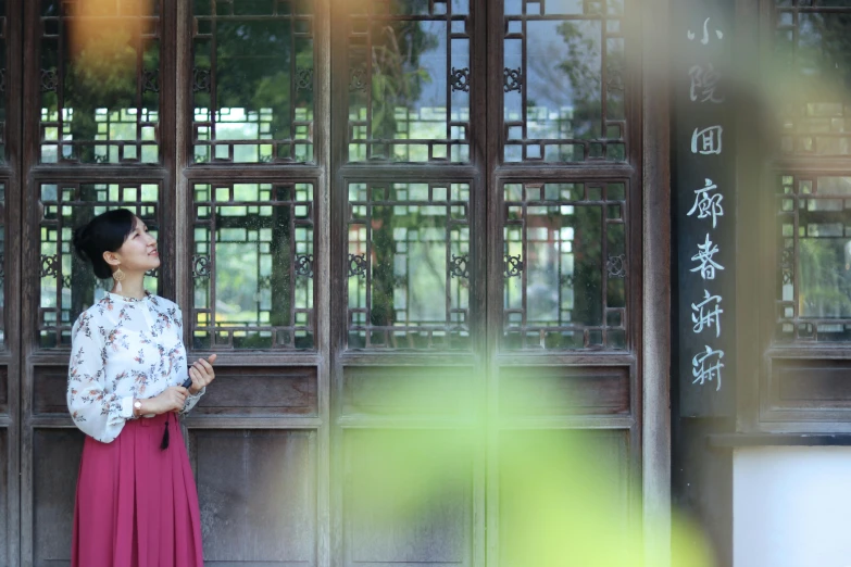 a woman standing in front of a wooden building, inspired by Xu Xi, happening, 15081959 21121991 01012000 4k, vacation photo, ancient garden behind her, promo image