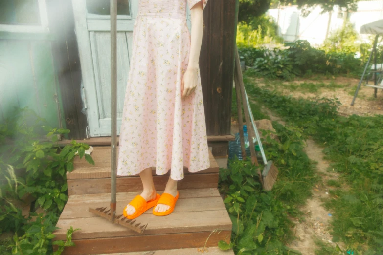 a woman standing on the steps of a house, inspired by Carl Larsson, unsplash, wearing pink flip flops, wearing dress, けもの, outdoor photo