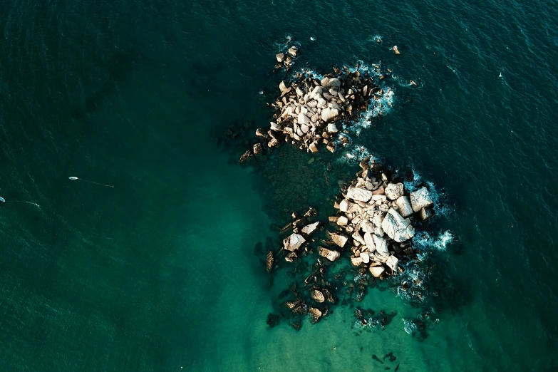 a large body of water surrounded by rocks, by Adam Marczyński, pexels, minimalism, aerial view cinestill 800t 18mm, sea - green and white clothes, ((rocks))