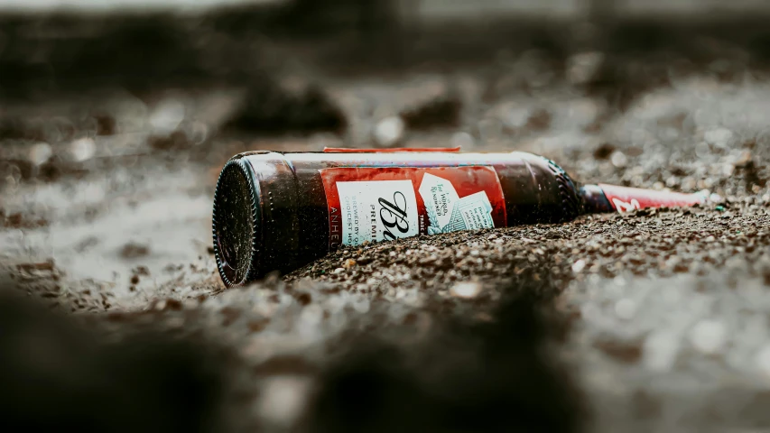 a bottle of beer sitting on top of a sandy beach, pexels contest winner, graffiti, blood on sand, brown, thumbnail, rum