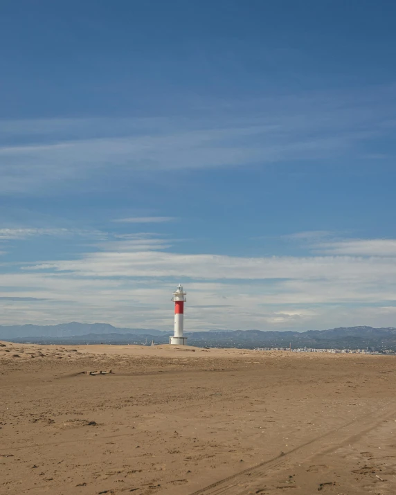 a red and white lighthouse sitting on top of a sandy beach, albert ramon puig, desert transition area, lgbtq, split near the left