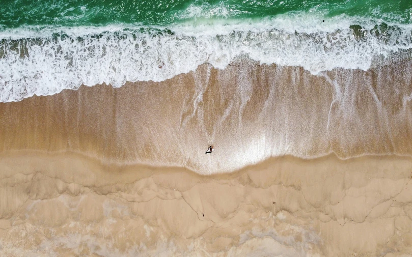 a person riding a surfboard on top of a sandy beach, pexels contest winner, minimalism, birds eye, australia, currents, 8k resolution”