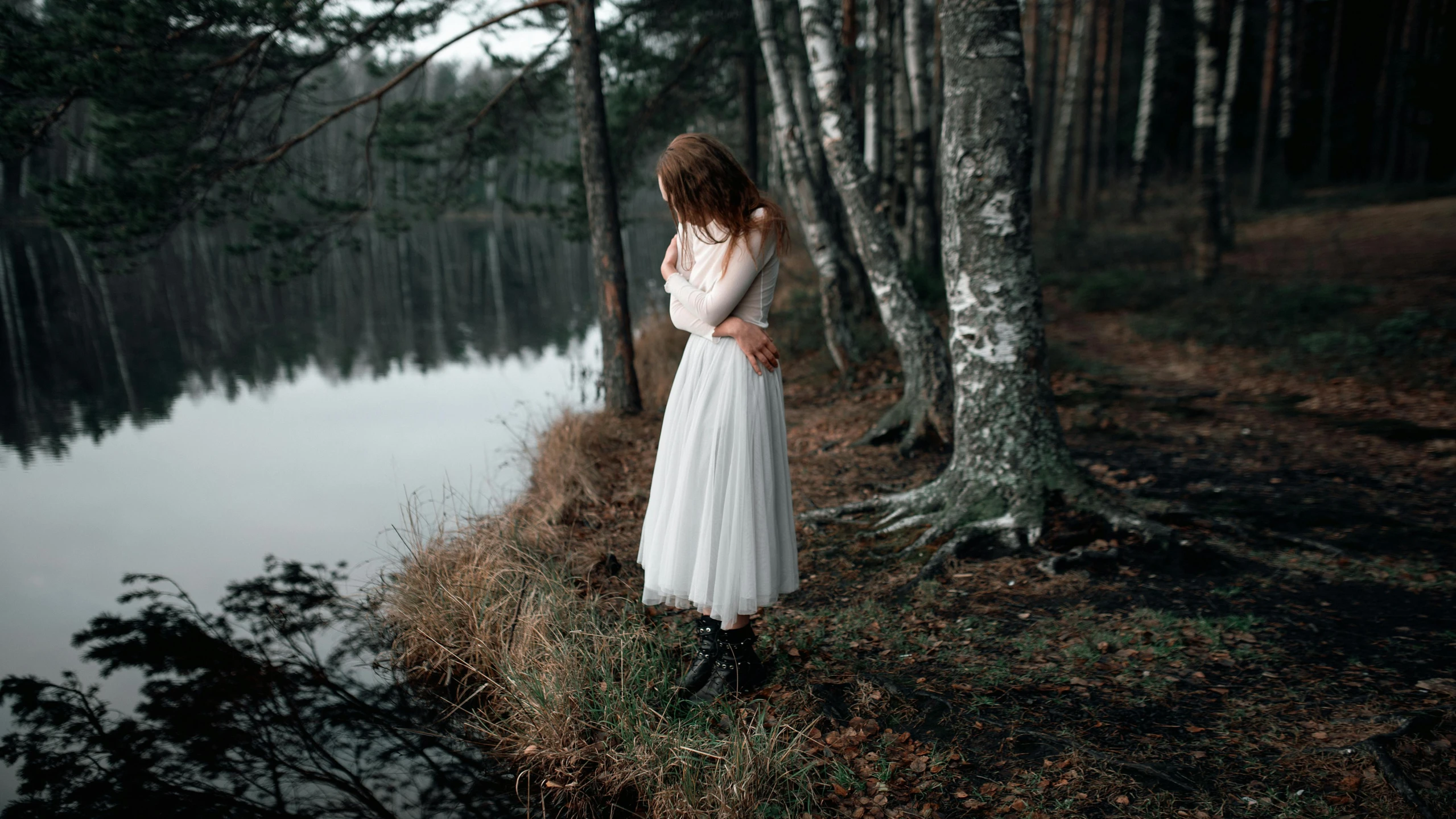 a woman in a white dress standing next to a body of water, a picture, inspired by Elsa Bleda, pexels contest winner, romanticism, in the wood, teenage girl, with a sad expression, wearing a white folkdrakt dress
