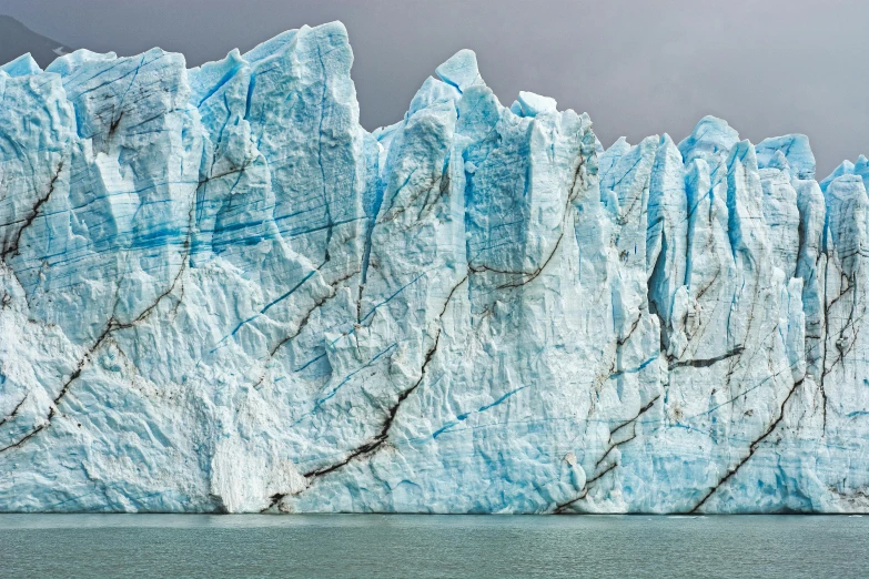 a large glacier in the middle of a body of water, by Alison Geissler, pexels contest winner, hyperrealism, chiseled jaw, pillars of ice background, panoramic photography, 2040
