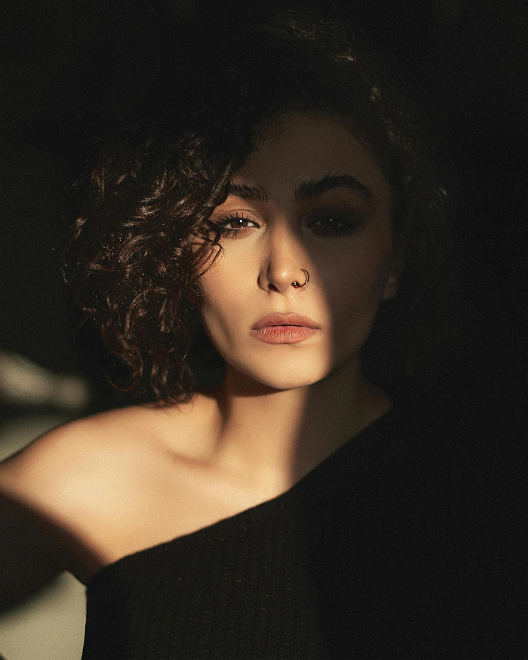 a woman in a black dress posing for a picture, a character portrait, trending on pexels, short curly hair, middle eastern skin, meredit frampton style, light coming through