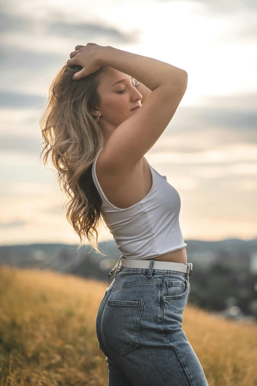 a woman standing on top of a grass covered hillside, trending on pexels, renaissance, wearing tank top, long ashy hair | gentle lighting, sydney sweeney, belly button showing