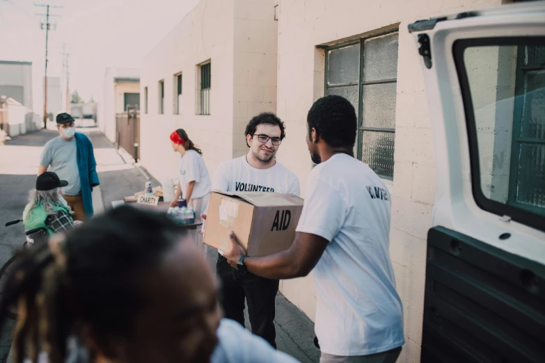 a group of people loading boxes into a van, by Francis Helps, unsplash, happening, los angeles 2 0 1 5, avatar image, offwhite, hunger
