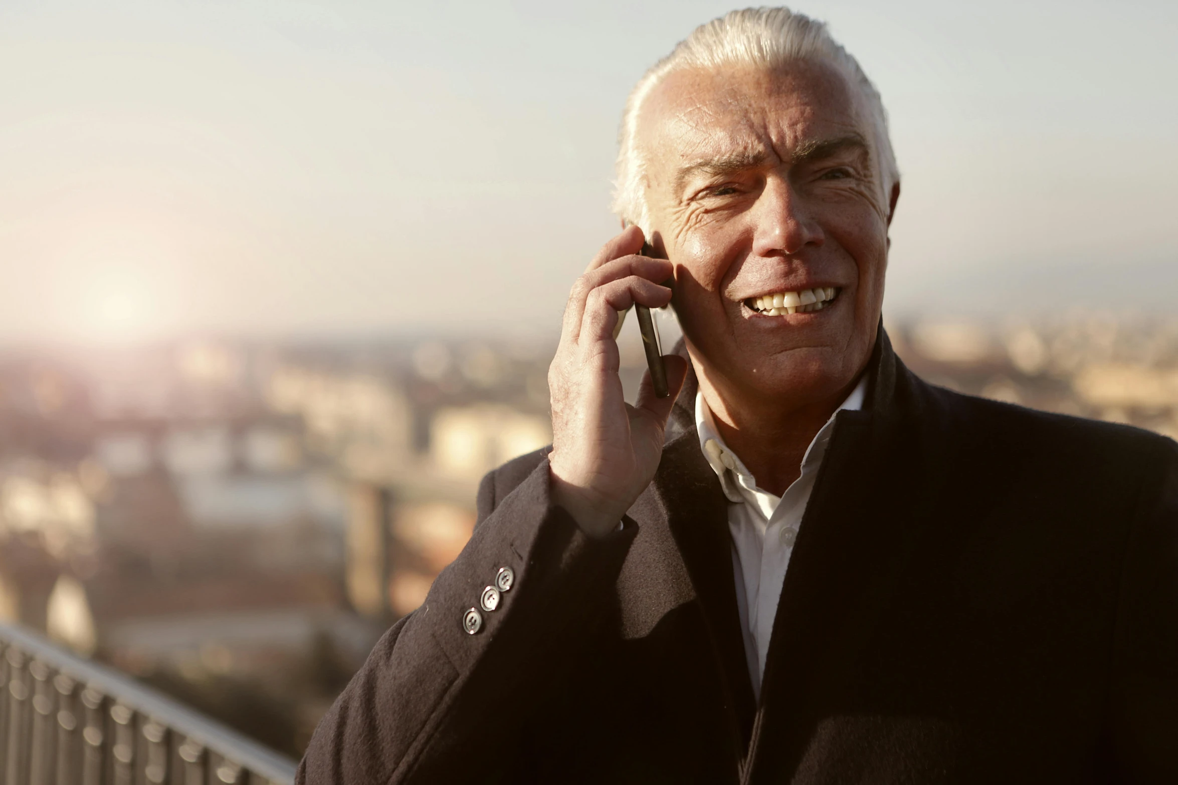 a close up of a person talking on a cell phone, a photo, white haired, smiling man, selling insurance, morning sun